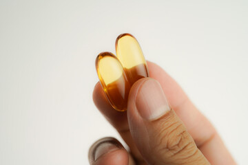 Male hand holding Fish oil capsules with omega 3, omega 9, vitamin D, vitamin E, Cod liver oil