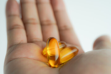 Male hand holding Fish oil capsules with omega 3, omega 9, vitamin D, vitamin E, Cod liver oil