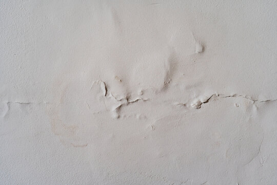 Pared blanca con humedad, grietas y desprendimiento de pintura