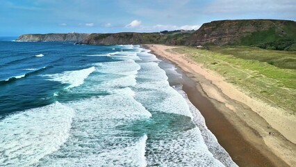 Experience breathtaking coastal views with waves crashing on a sandy beach, a mesmerizing sight