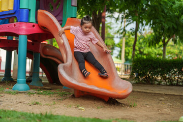 happy toddler baby girl sliding and playing at playground