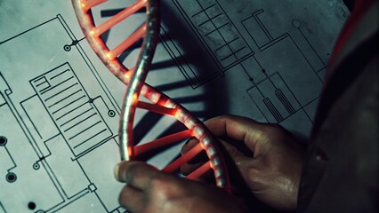 Futuristic Identity Concepts in Manufacturing Aesthetics. A person holds a DNA double helix model over a technical blueprint, symbolizing the intersection of genetics and technology.