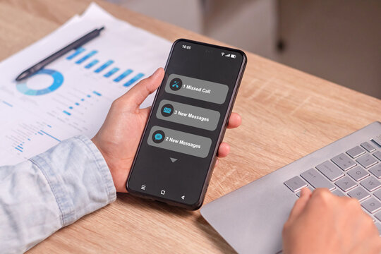 A business woman holding a smartphone with notifications of missed calls and new messages on her phone screen