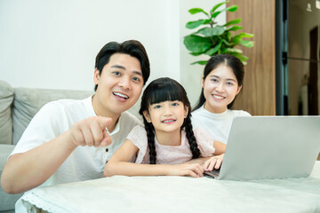 Fototapeta premium Asian family using laptop on sofa at home