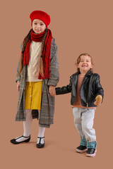 Cute little happy girls in warm clothes on brown background