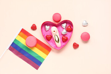 Heart shaped gift box with vibrator, rainbow LGBT flag and sweets on beige background. Valentine's...