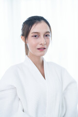 Portrait of a young Asian woman in a white bathrobe posing confidently with soft natural lighting.