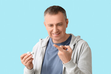 Mature man with contact lens and case on blue background
