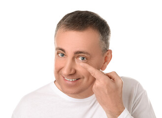Mature man putting in contact lenses on white background