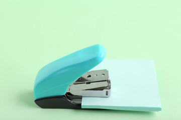 Blue stapler with sticky notes on green background