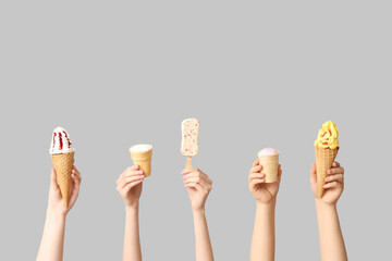 Female hands with different sweet ice-cream on grey background