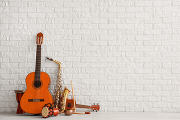 Different musical instruments near white brick wall