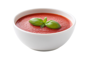 Fresh tomato soup in white bowl garnished with basil leaves, cut out
