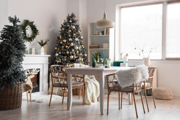 Interior of light dining room with table, fireplace and Christmas trees