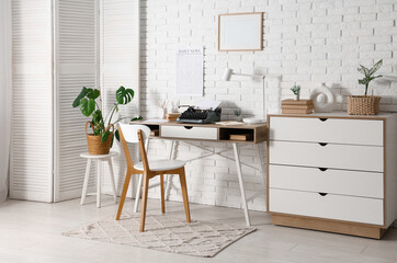 Stylish workspace with vintage typewriter, books and newspaper in light living room