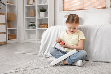 Cute little girl playing with screwdriver and extension cord in bedroom. Child at risk