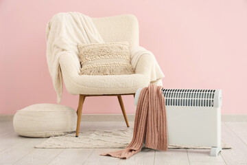 Interior of stylish living room with modern convector heater, pouf and cozy white armchair