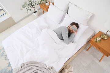Morning of handsome man with mask sleeping in bedroom, top view