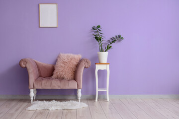 Stylish sofa and houseplant on stool near purple wall in room
