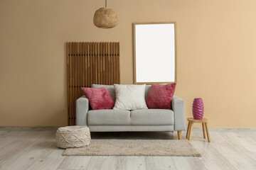 Interior of modern living room with folding screen, painting and purple pillows on grey sofa