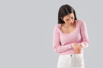 Obraz premium Young woman suffering from wrist pain on light background