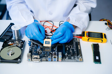 The technician is putting the CPU on the socket of the computer motherboard. electronic engineering...