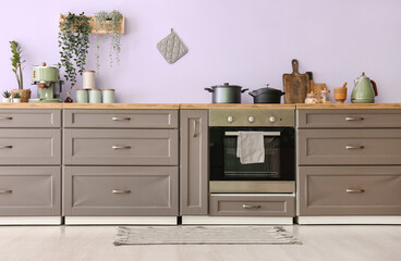 Interior of modern kitchen with grey counters, utensils and plants
