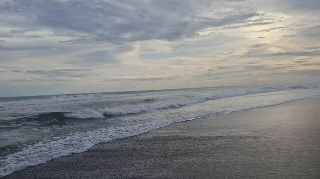 A scenic footage of soft ocean waves gently reaching the shore as the sunset reflects on the wet sand. The dramatic sky adds emotional depth and a cinematic mood. Perfect for relaxation themes, ambien