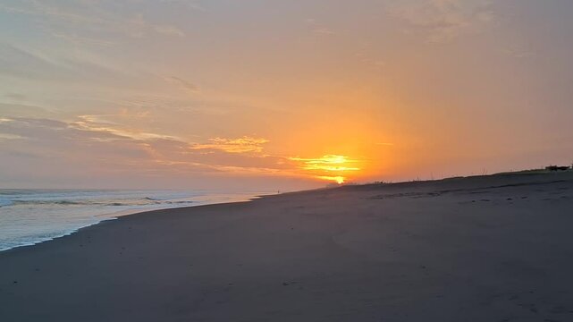 The Beauty of Sunset on Tropical Black Sand Beach with Golden Sky and Gentle Waves, Orange Light Reflection on the Water Surface, Calm and Exotic Atmosphere Suitable for Relaxation Videos