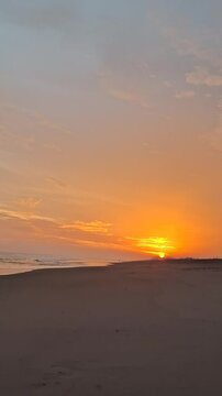 Tropical Sunset Scenery on Black Sand Beach with Bright Golden Sky and Gentle Waves, Color Gradation from Yellow to Orange Creating a Peaceful Atmosphere, Harmonious Combination of Sky and Sea, Perfec