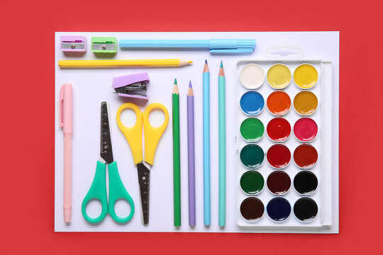 Set of school stationery with paints on red background