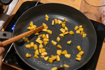 Stir-frying golden potatoes in black pan