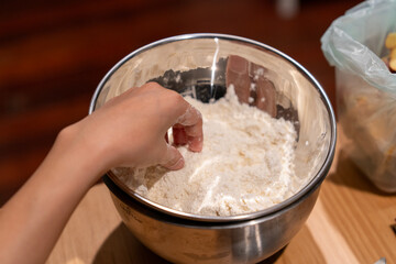 Home Baker’s Hand Gently Mixing Dough in Stainless Steel Bowl