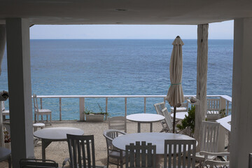 Ocean View Through Cafe Interior with Terrace Seating and Folded Sun Umbrella