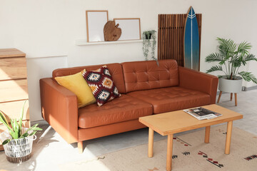 Interior of living room with surfboard, folding screen and brown sofa