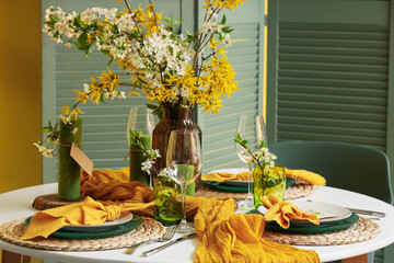 Table setting with blossoming branches and candles in room