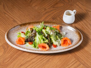 Smoked Salmon Salad with Mixed Greens and Dressing on Rustic Plate