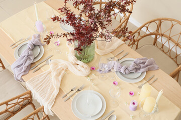 Table setting with blossoming branches and burning candles in room, top view