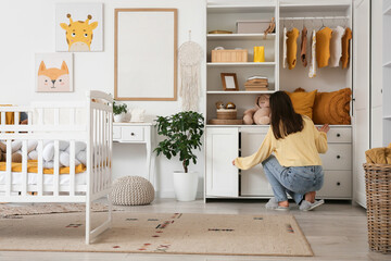 Young woman opening drawer in nursery, back view
