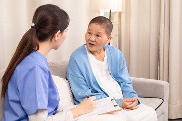 Obraz premium Young nurse in uniform listening attentively to an senior woman on a couch, expressing support and empathy in a friendly conversation about health and wellbeing, healthcare, medical, take care.