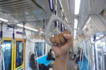 Close up of male hand holding a hand grip in commuter train