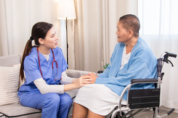Obraz premium Senior woman in wheelchair discussing health with nurse on sofa, both smiling and sharing emotional connection, illustrating trust and support in home care setting, healthcare, illness, patient.