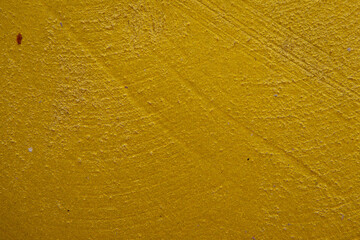 close-up shot of a textured gold yellow concrete surface. The rough and slightly uneven texture, along with subtle variations in the gold yellow hue, creates a visually interesting background.