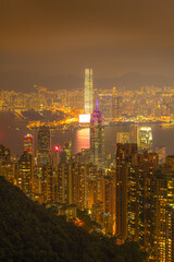 Hong Kong city and skyscrapers at night from a high mountaintop vantage point. The city lights create a stunning urban landscape.