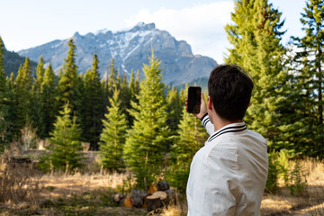 Man photographing mountains from a forest clearing.