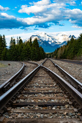 Obraz premium Converging train tracks with mountains and clear blue sky in the background