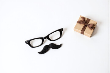 cup of coffee with a mustache on it next to a gift box