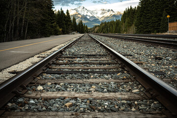 Train tracks leading into forest and mountains, dramatic and moody