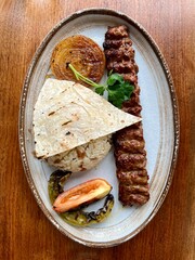 Adana Kebap close up. Turkish food. Grilled lamb serve with grill tomato, onion, hot pepper.
