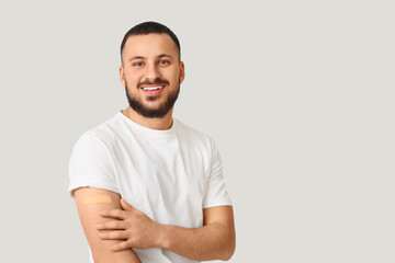 Young man with applied medical patch on light background. Immunization concept